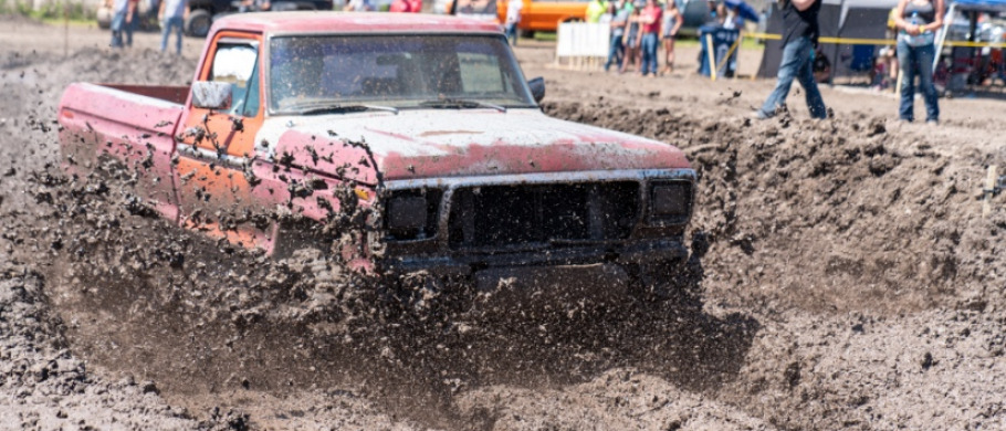 A pickup truck driving through the mud during a fair's mud run